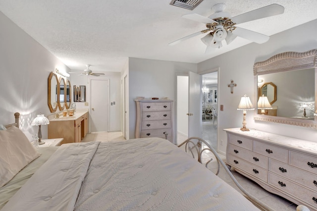 bedroom featuring ceiling fan, ensuite bathroom, and a textured ceiling