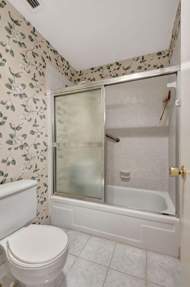 bathroom featuring bath / shower combo with glass door, tile patterned floors, and toilet