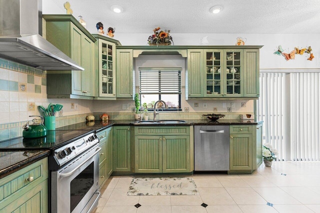 kitchen featuring wall chimney range hood, green cabinets, sink, and appliances with stainless steel finishes