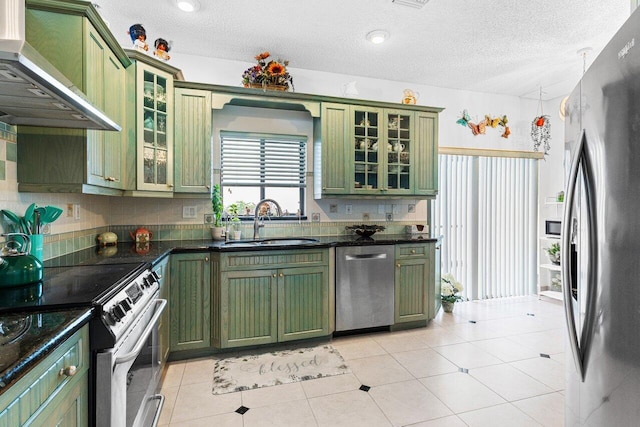 kitchen featuring wall chimney range hood, sink, stainless steel appliances, a textured ceiling, and green cabinetry