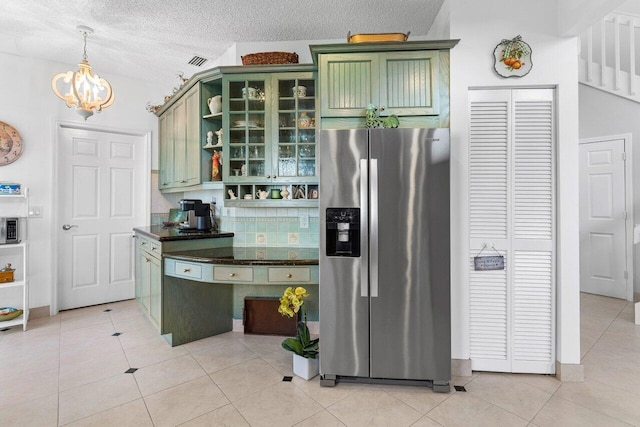 kitchen with light tile patterned floors, green cabinets, an inviting chandelier, a textured ceiling, and stainless steel fridge with ice dispenser