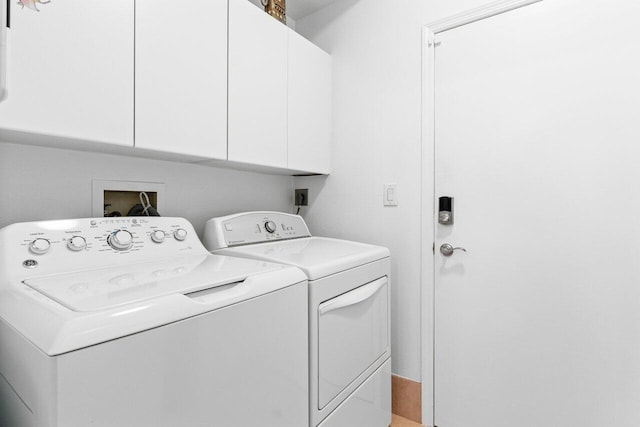 clothes washing area featuring cabinets and washer and clothes dryer