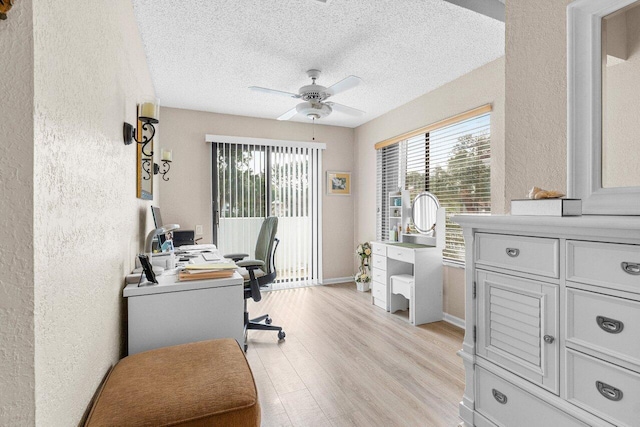 home office with ceiling fan, plenty of natural light, a textured ceiling, and light hardwood / wood-style floors