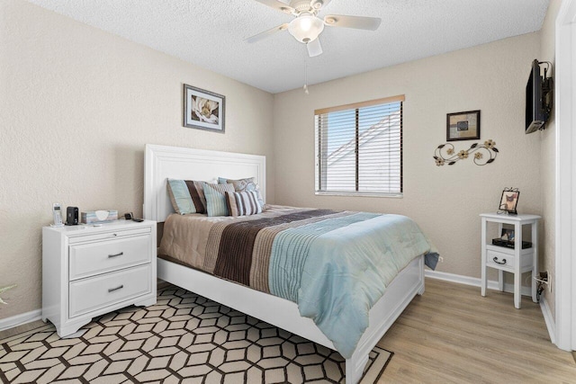 bedroom with ceiling fan, a textured ceiling, and light hardwood / wood-style flooring