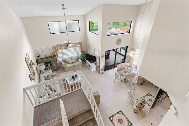 living room featuring light tile patterned floors, a textured ceiling, ceiling fan, and a high ceiling