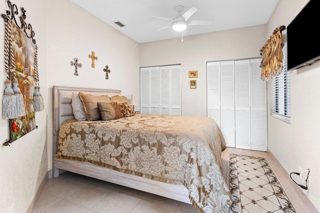 tiled bedroom featuring ceiling fan and multiple closets