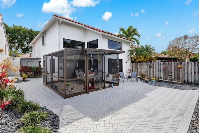 rear view of property with a sunroom and a patio