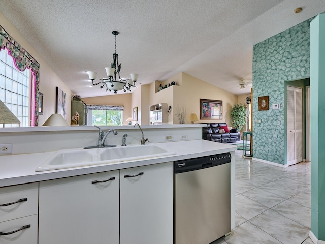 kitchen with lofted ceiling, sink, white cabinets, decorative light fixtures, and stainless steel dishwasher