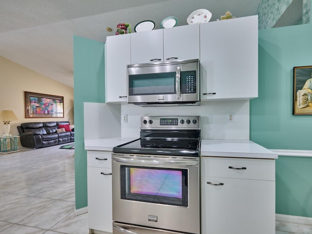 kitchen with stainless steel appliances, vaulted ceiling, and white cabinets