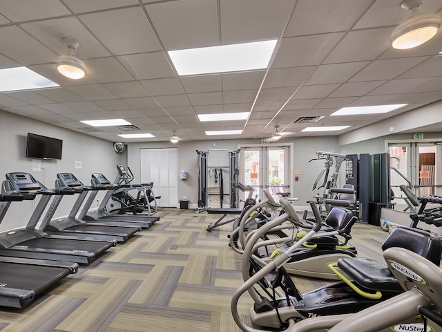 exercise room with french doors, light carpet, and a drop ceiling