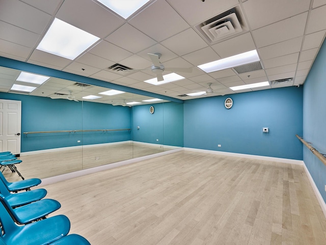 interior space with a drop ceiling, hardwood / wood-style floors, and ceiling fan