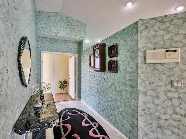 hallway with vaulted ceiling, a textured ceiling, and light tile patterned floors