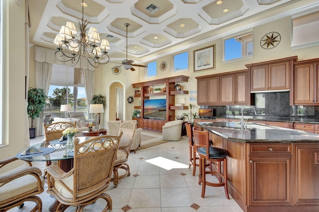 kitchen with hanging light fixtures, a towering ceiling, ornamental molding, decorative backsplash, and a chandelier