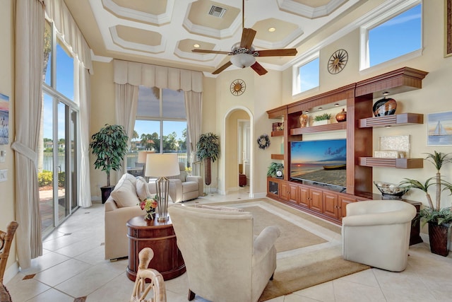 tiled living room featuring a healthy amount of sunlight, a towering ceiling, ornamental molding, and coffered ceiling