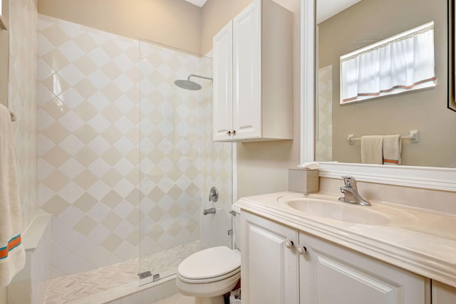 bathroom with vanity, toilet, and tiled shower