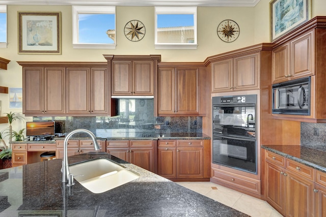 kitchen with light tile patterned flooring, sink, dark stone counters, decorative backsplash, and black appliances