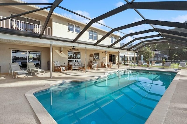 view of pool with a patio, ceiling fan, and glass enclosure