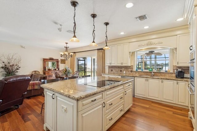 kitchen with sink, a center island, pendant lighting, and cream cabinets