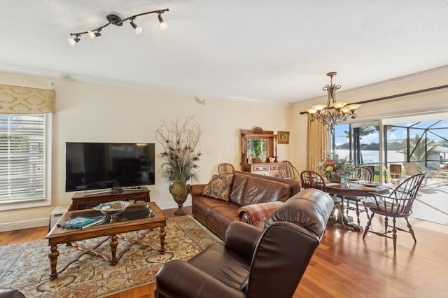 living room with a notable chandelier, crown molding, baseboards, and wood finished floors