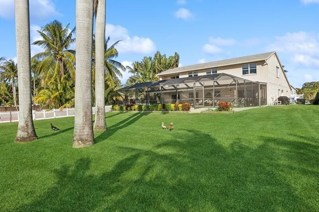 rear view of house featuring glass enclosure and a lawn