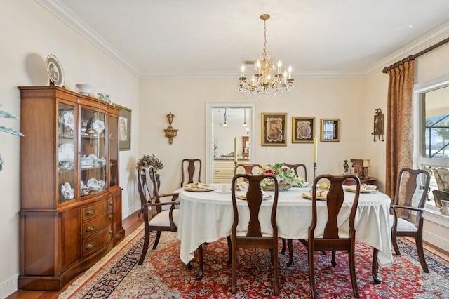 dining area featuring ornamental molding, light wood-type flooring, a notable chandelier, and baseboards