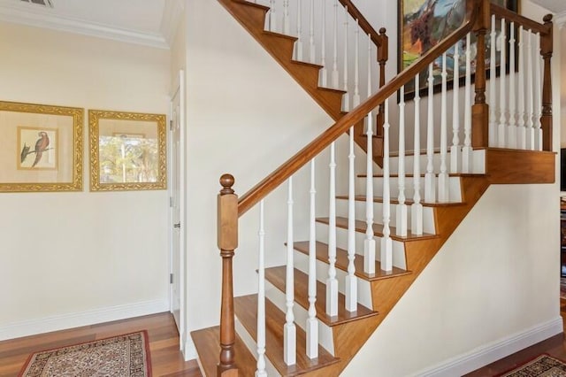 stairs with crown molding, baseboards, and wood finished floors