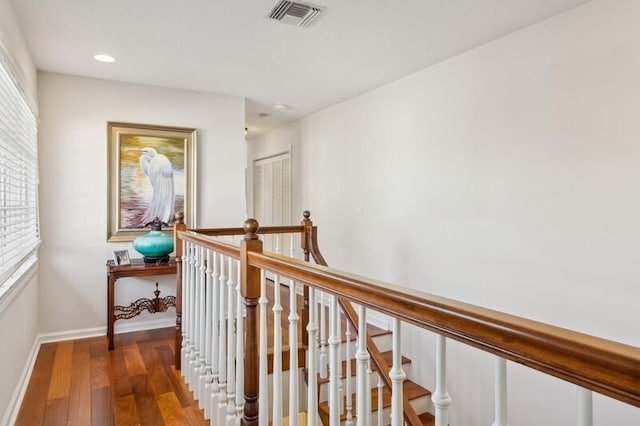 hall featuring baseboards, visible vents, wood finished floors, an upstairs landing, and recessed lighting