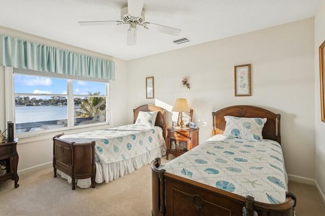 carpeted bedroom with a water view and ceiling fan