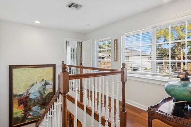 hall with recessed lighting, wood finished floors, visible vents, an upstairs landing, and baseboards