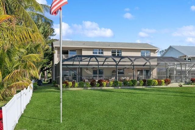 back of house with a lawn, a lanai, and fence