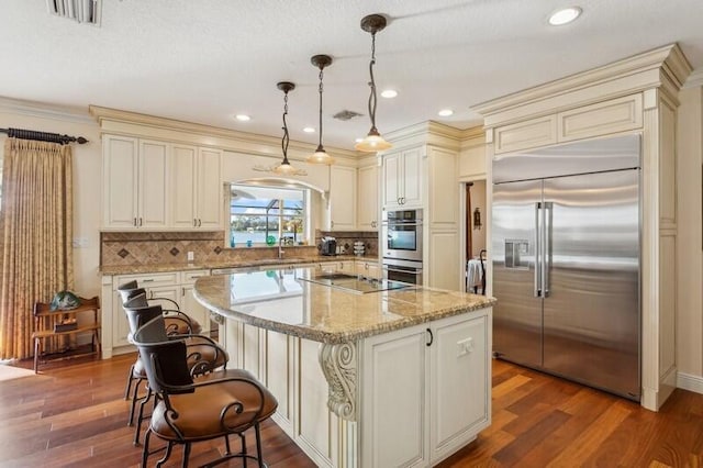 kitchen with appliances with stainless steel finishes, a kitchen island, and cream cabinets