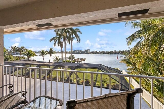 dock area with a water view, a yard, and glass enclosure