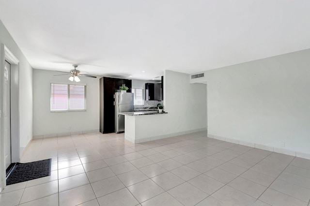 unfurnished living room with light tile patterned floors, visible vents, baseboards, and ceiling fan