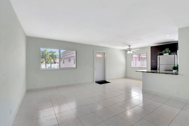 unfurnished living room featuring light tile patterned floors, baseboards, and ceiling fan