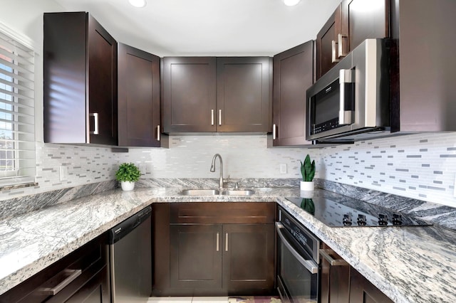 kitchen with a sink, stainless steel appliances, light stone countertops, and decorative backsplash