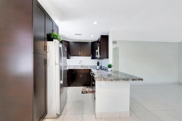 kitchen with light stone counters, visible vents, a peninsula, light tile patterned flooring, and backsplash