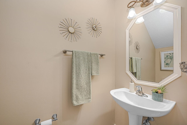 bathroom featuring lofted ceiling and sink