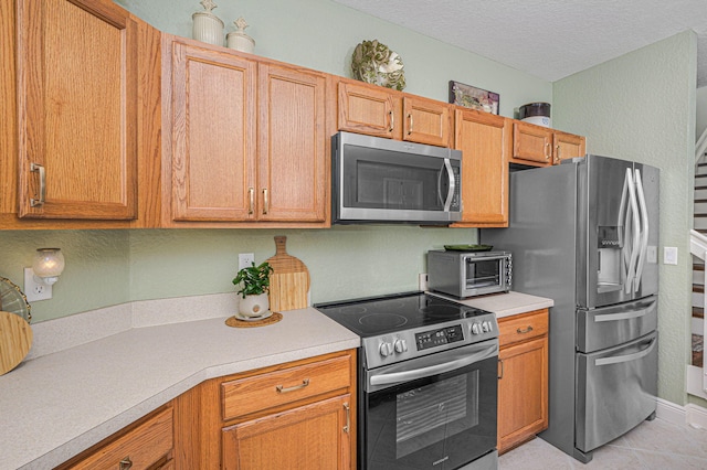 kitchen featuring appliances with stainless steel finishes, a textured ceiling, and light tile patterned floors