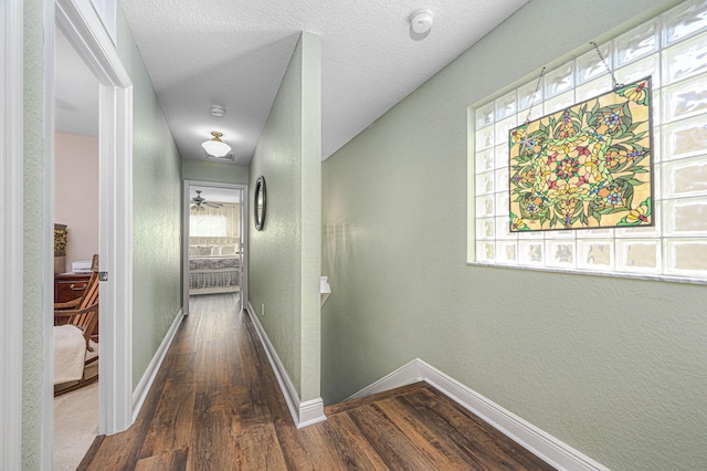 corridor with dark hardwood / wood-style flooring, plenty of natural light, and a textured ceiling