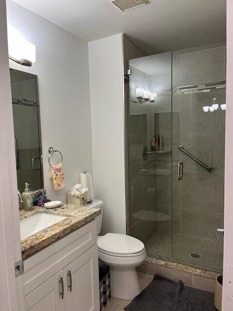 bathroom with tile patterned flooring, vanity, an enclosed shower, and toilet