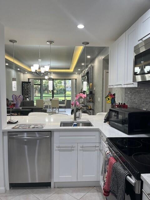 kitchen featuring white cabinetry, sink, pendant lighting, and appliances with stainless steel finishes