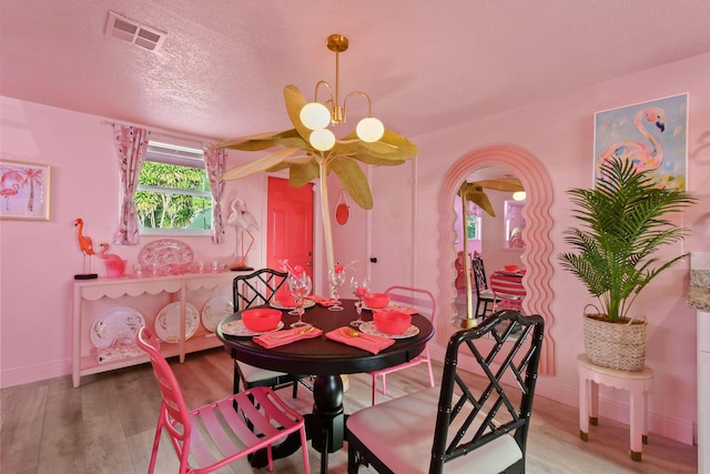 dining room featuring a textured ceiling, wood-type flooring, and a chandelier