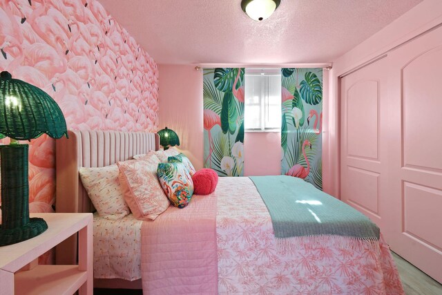 bedroom with light hardwood / wood-style floors, a closet, and a textured ceiling