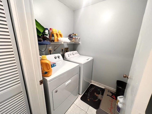 laundry area with washing machine and dryer and light tile patterned floors