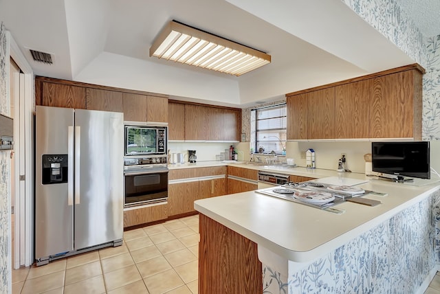 kitchen with built in microwave, stainless steel refrigerator with ice dispenser, oven, and kitchen peninsula