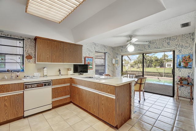 kitchen with white appliances, plenty of natural light, kitchen peninsula, and sink