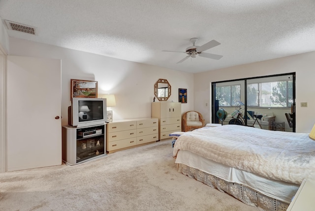 carpeted bedroom featuring ceiling fan and a textured ceiling