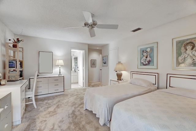 carpeted bedroom with ensuite bathroom, ceiling fan, and a textured ceiling