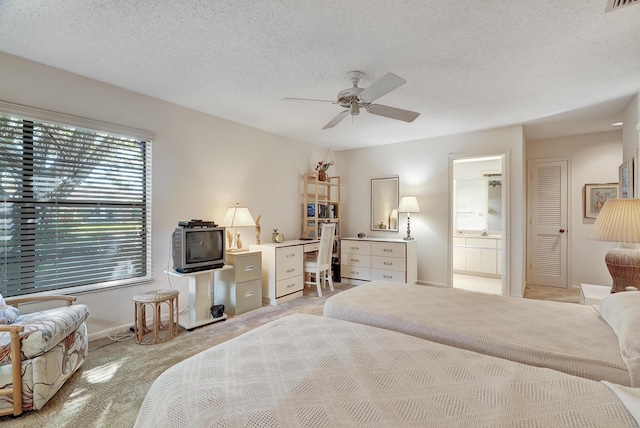 carpeted bedroom featuring ceiling fan, connected bathroom, and a textured ceiling