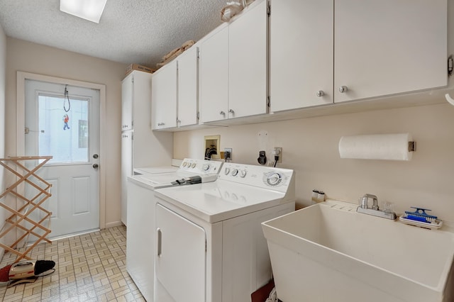 washroom with washer and dryer, sink, a textured ceiling, and cabinets